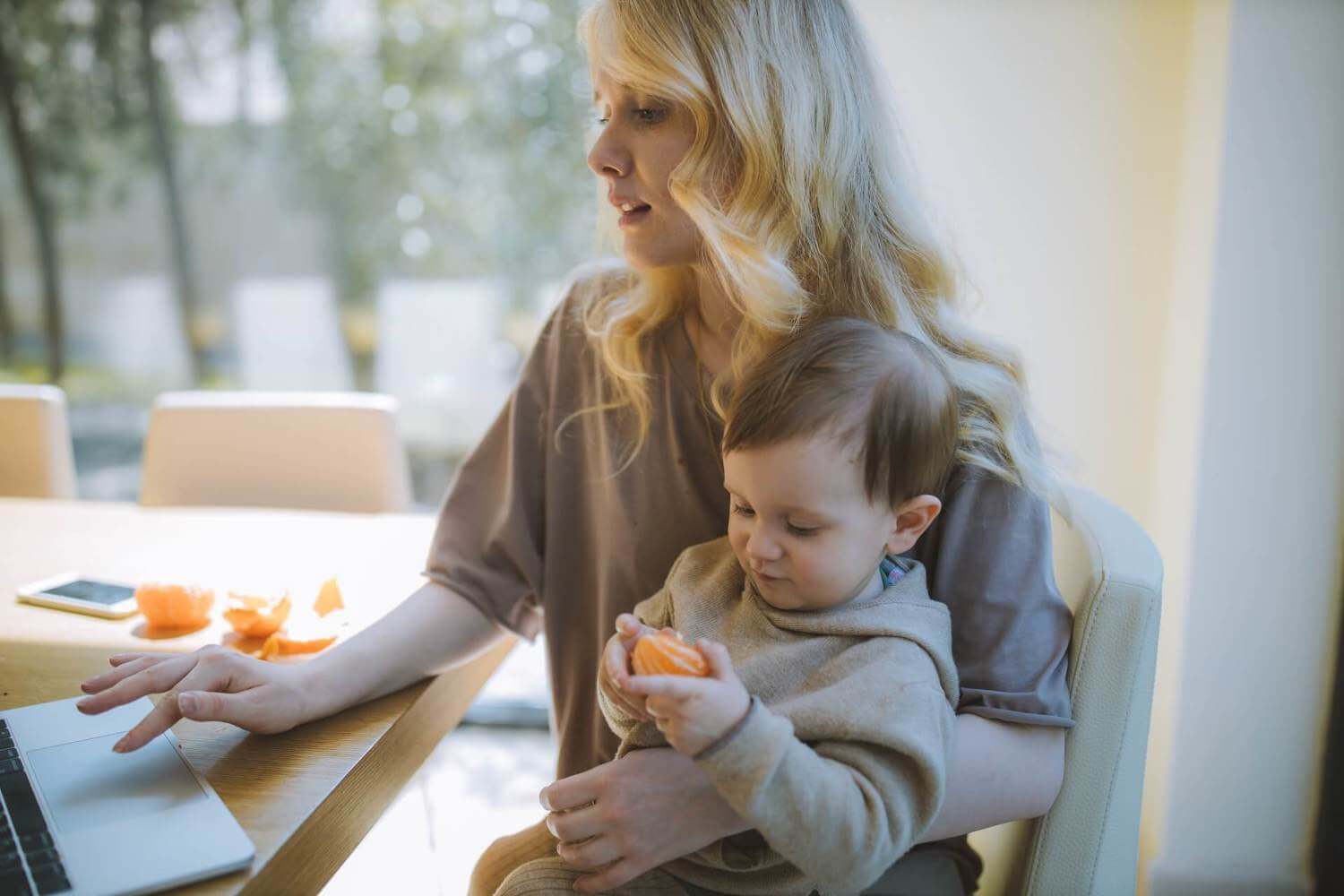 woman sitting at desk holding her baby while working from home