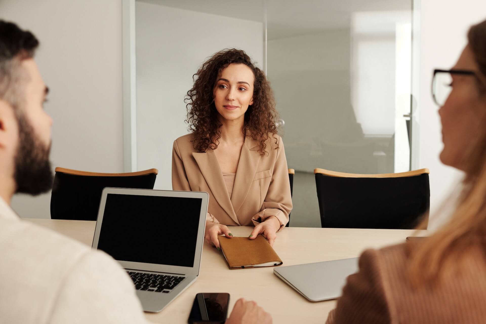 a woman having an interview with two people as part of the recruitment process