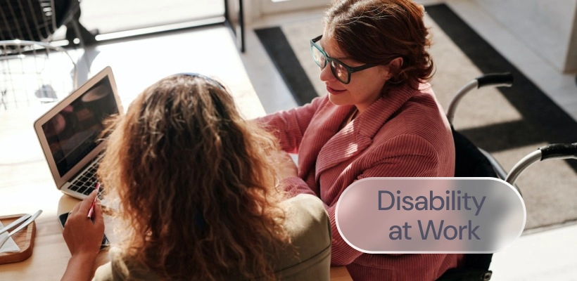 Two women talking in a meeting room with the label: Disability at Work