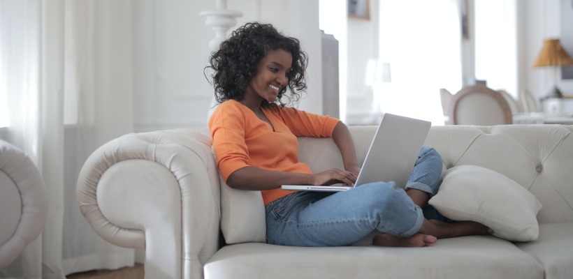 remote worker on her laptop smiling because of employer's good employee retention strategy