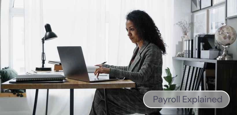 A woman working at her desk, with the label: Payroll explained